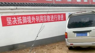 A banner hanging on the wall, reading “Resolutely Guard Against Overseas Infiltrations via Religious Means.”
