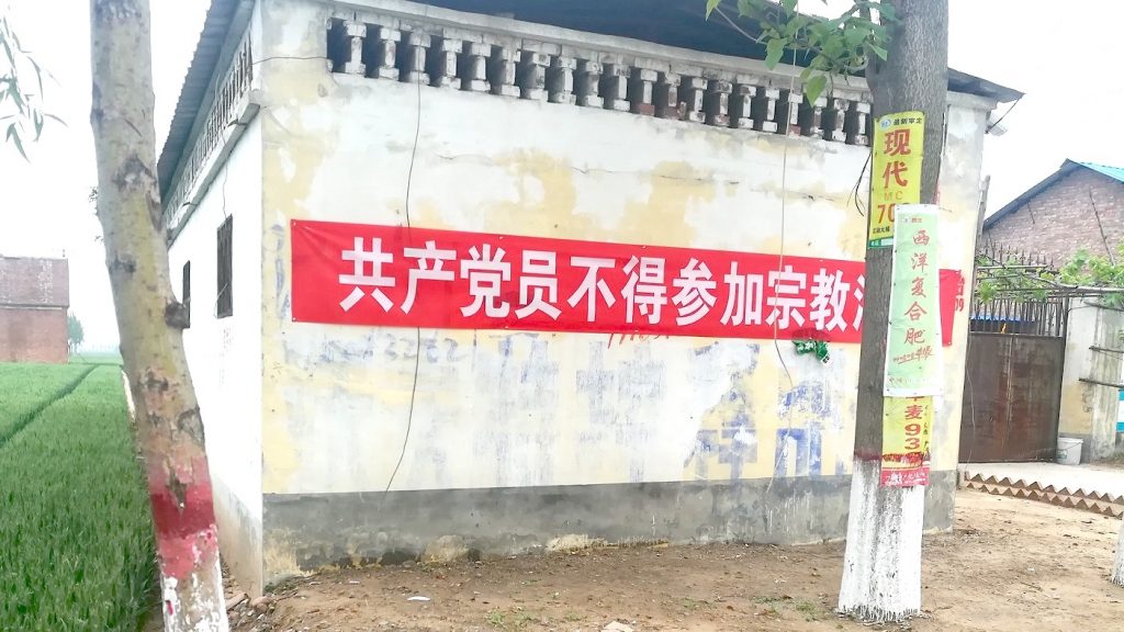 A banner hanging on the wall, reading “Communist Party Members Cannot Participate in Religious Activities.”