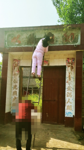 Mentre la figlia sta gettando del cemento sopra il pannello per coprire i caratteri che significano “Emanuele”, la signora Guo osserva con un senso di impotenza.