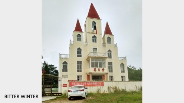 Rimozione della croce dalla chiesa di Enzhu nel villaggio di Menghui, borgo di Kangle, città di Yichun, mentre la bandiera nazionale è issata davanti alla chiesa