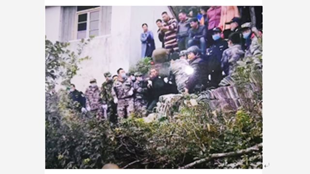Agenti del PCC mentre trascinano giù dalla montagna, afferrandolo per le mani, un anziano abitante del villaggio che sorvegliava il tempio