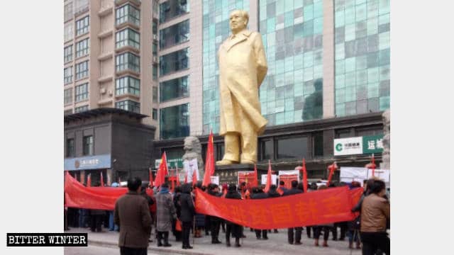 Un gruppo di manifestanti si riunisce sotto una grande statua di bronzo di Mao Zedong nel Giardino Culturale dei Lavoratori per pronunciare giuramenti solenni in suo onore
