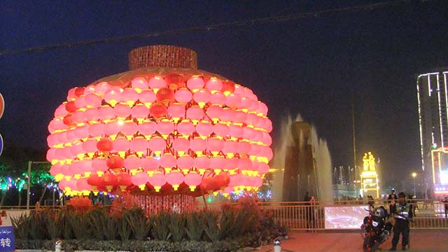 Lanterne cinesi decorano la piazza principale di Hotan e sul lato opposto si trova una statua di Mao Zedong che lo ritrae mentre, nel 1958, stringe la mano a un contadino uiguro di nome Kurban Tulum