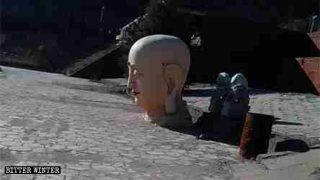 La testa abbandonata nel cortile è tutto ciò che rimane della statua del Buddha alta 18 metri