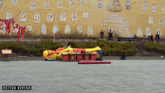 Dopo essere stata smantellata, la statua di Guanyin che stilla acqua è stata posta su un lato e coperta con un telo