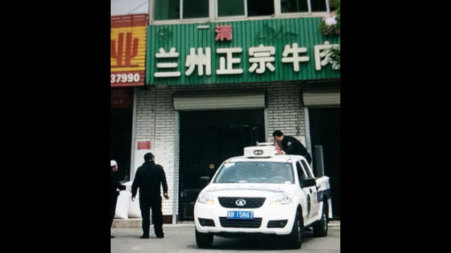 Poliziotti mentre smantellano i caratteri arabi che significano halal