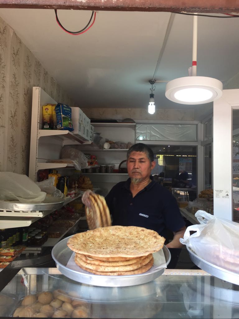 Un panettiere di Kashgar mostra con orgoglio il pane "naan" appena tolto dal forno Tandoor