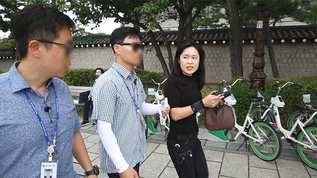 Un'irritata O Myung-ok viene fermata dalle guardie di sicurezza mentre tenta di lanciarsi verso i manifestanti durante la conferenza stampa