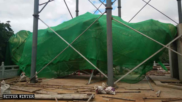 La statua della Guanyin è stata posata a terra e coperta con una rete verde
