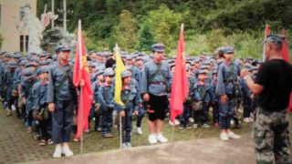 Gli studenti indossano l’uniforme dell’Esercito Popolare di Liberazione e portano zaini con stampati il ritratto del presidente Mao e lo slogan «Servire il popolo»