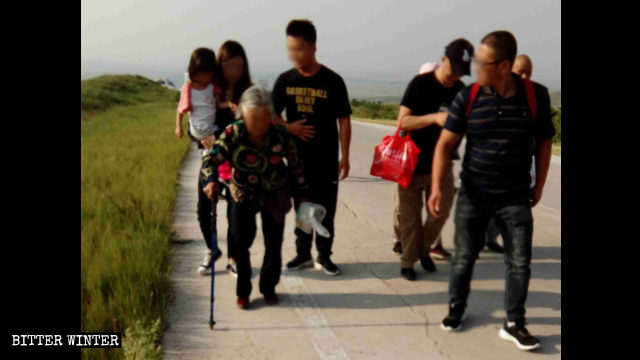 Una donna anziana, con i capelli bianchi, ha dovuto usare un bastone per raggiungere il luogo del pellegrinaggio, in cima al monte