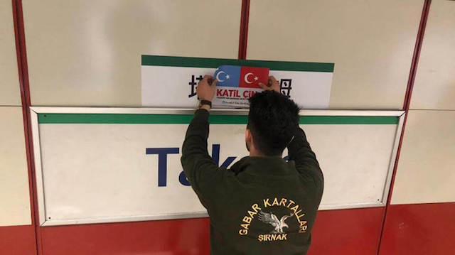 Un giovane turco, simpatizzante per la causa uigura, copre l’indicazione in mandarino della fermata di piazza Taksim della linea tramviaria con le bandiere del Turkestan orientale e della Turchia, insieme alla scritta «katil çin», ovvero «assassino cinese»