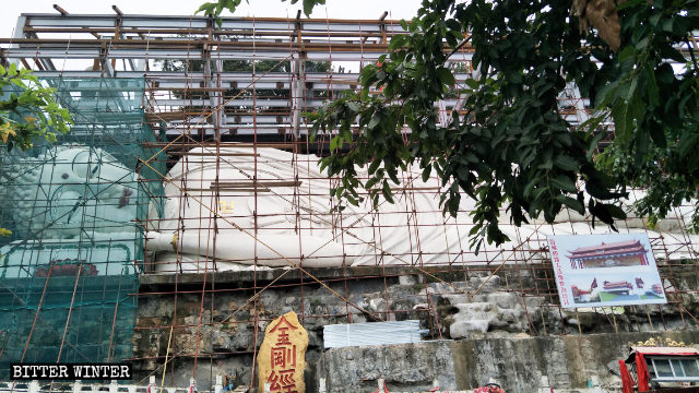 La grande scultura del Buddha disteso viene coperta
