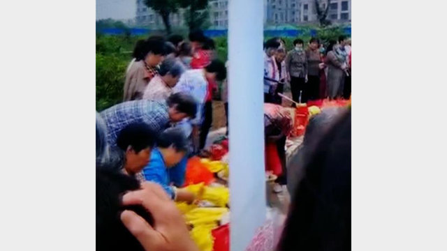 La gente brucia incenso e banconote davanti alla statua di Mao Zedong
